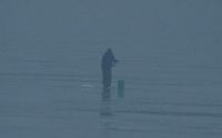 image of an ice fisherman standing in the fog