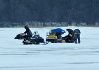 image of snowmobiles rigged with portable ice fishing shelters